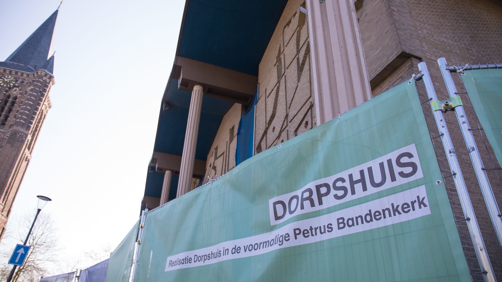 Het hek om de voormalige Sint-Petrus' Bandenkerk met een impressie van het nieuwe dorpshuis