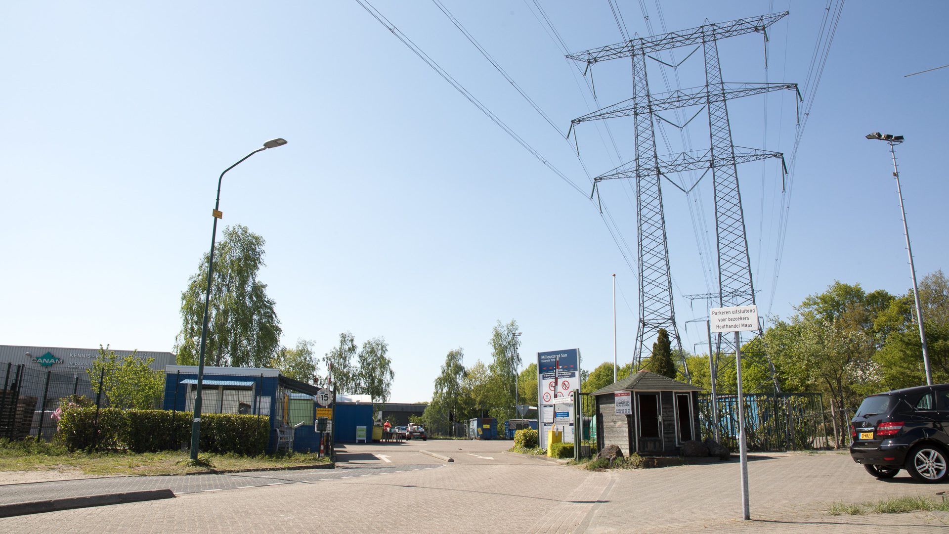 De ingang van de milieustraat in Son en Breugel onder een hoogspanningsmast