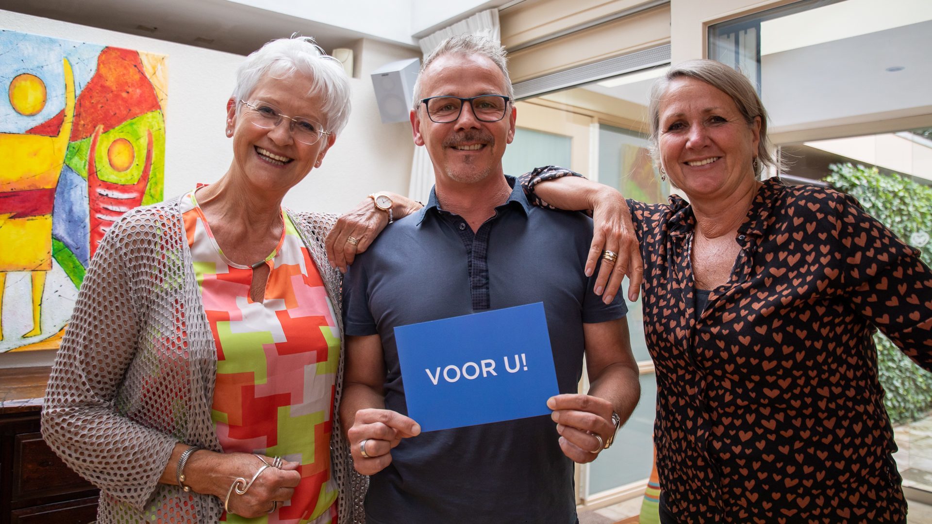 Marianne van der Putte, Stephen Philippi en Helga Helders met de blauwe ansichtkaart met Voor U