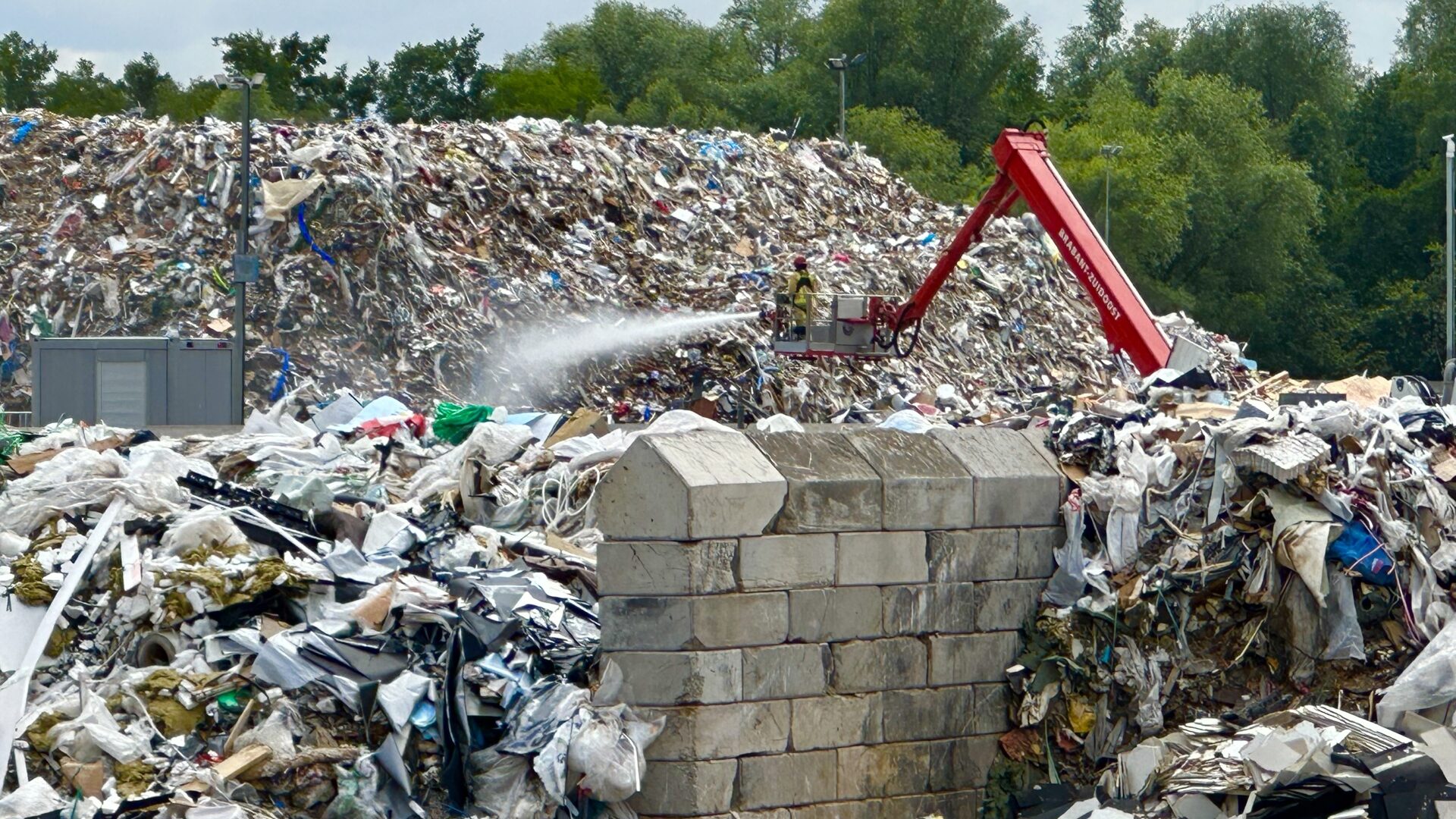 Brandweer in een hoogwerker blust het vuur bij recyclingbedrijf Baetsen